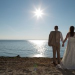 Brautpaar hält Händchen vor sonnigem Seepanorama