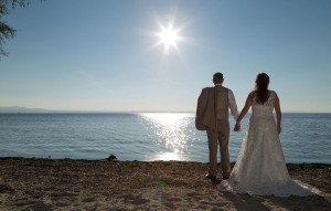 Brautpaar hält Händchen vor sonnigem Seepanorama